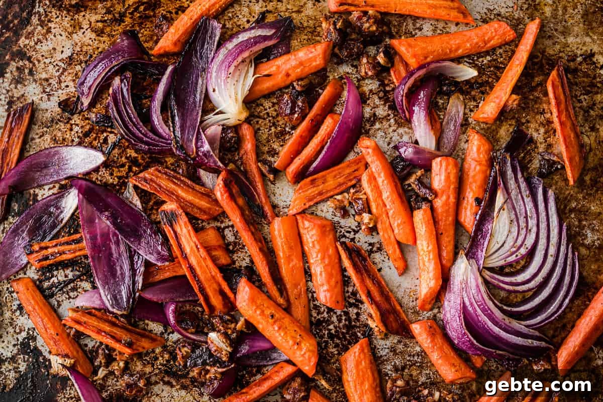 Oven-Roasted Carrots and Dates with Pistachio Pesto 7 Carrots and onions on a baking sheet after being roasted.