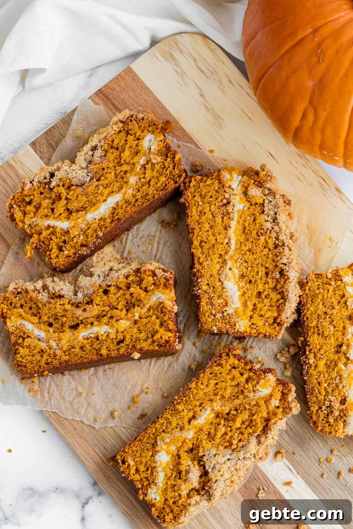 Pumpkin Cream Cheese Swirl Bread 3 slices of pumpkin cream cheese bread laying on a wooden cutting board