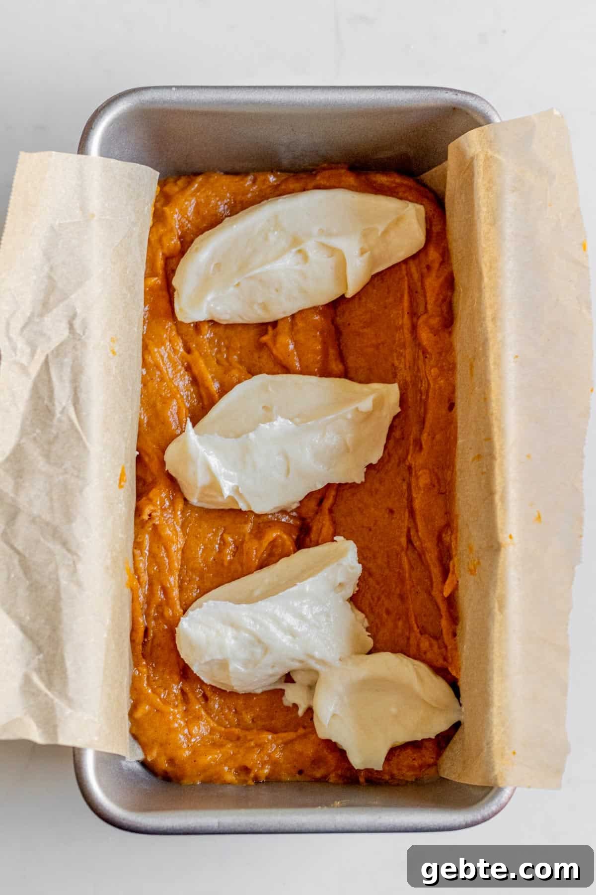 Pumpkin Cream Cheese Swirl Bread 5 dollops of cream cheese on top of pumpkin bread batter in a loaf pan