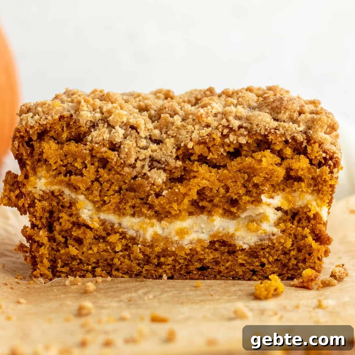 close up of loaf of pumpkin bread cut open showing cream cheese layer