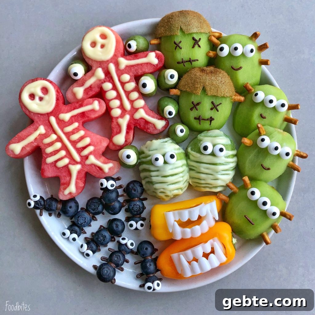 A plate of creatively arranged fruits and veggies makes healthy Halloween bites: watermelon skeletons, kiwi monsters, green apple mummies, blueberry spiders, and bell pepper mouths with teeth.