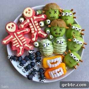 A plate of creatively arranged fruits and veggies makes healthy Halloween bites: watermelon skeletons, kiwi monsters, green apple mummies, blueberry spiders, and bell pepper mouths with teeth.