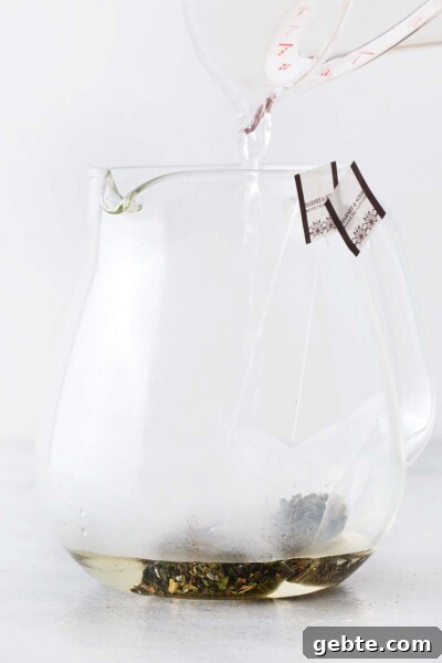 Pineapple Iced Tea Recipe — Tropical Summer Drink 5 Hot water being poured into teapot holding green tea bags.