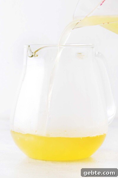 Pineapple Iced Tea Recipe — Tropical Summer Drink 7 Pineapple juiced being poured into teapot into brewed green tea.