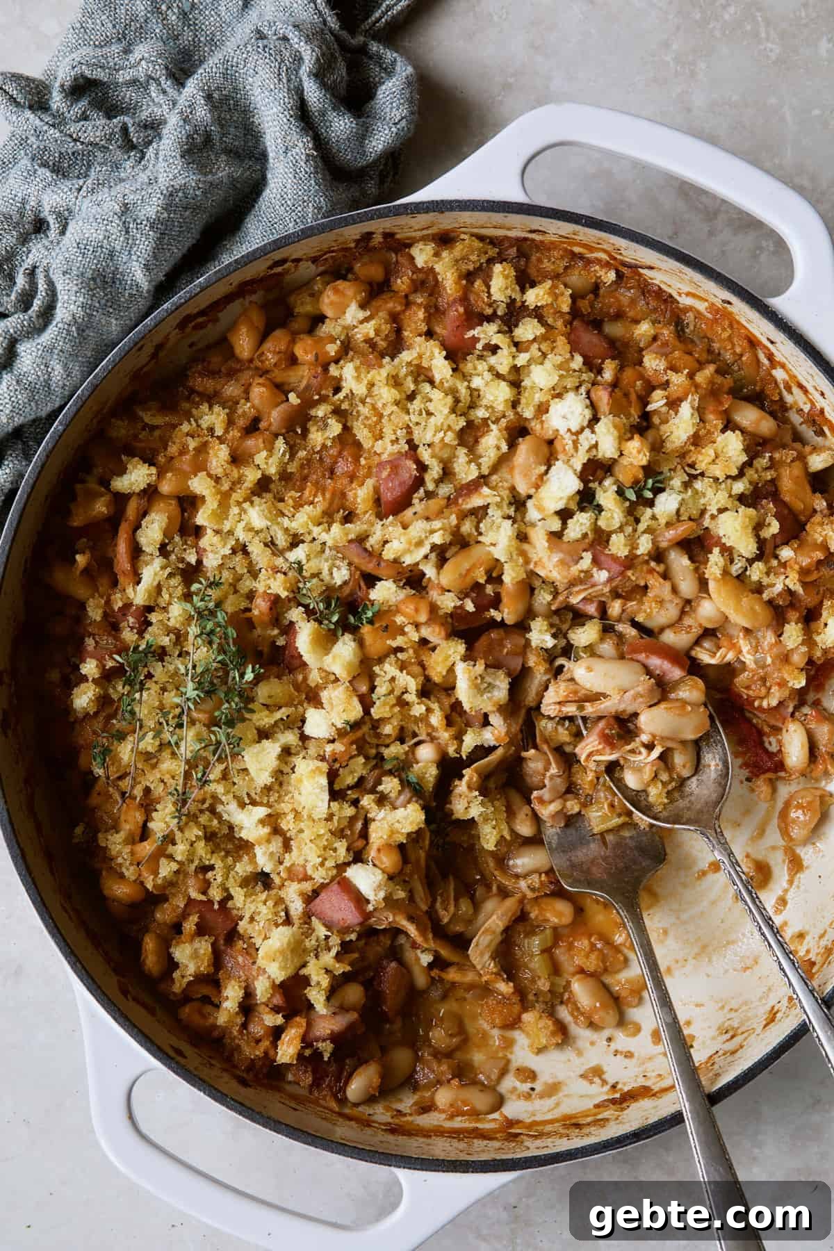 Photo of Easy Weeknight Chicken and Sausage Cassoulet after some has been served with serving utensils.