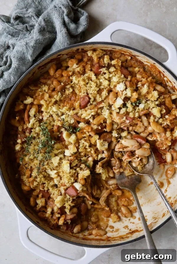 Photo of Easy Weeknight Chicken and Sausage Cassoulet after some has been served with serving utensils.