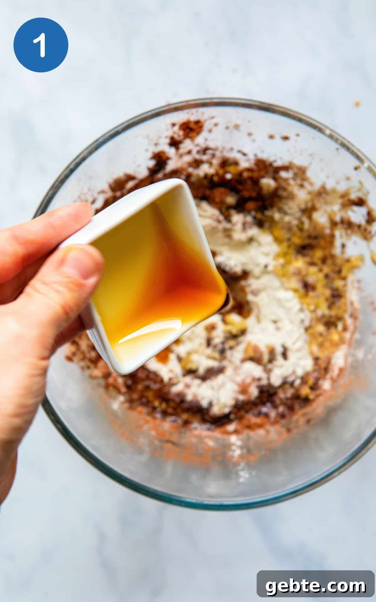 Hand pouring maple syrup into the Gluten Free Chocolate Cookies mix.
