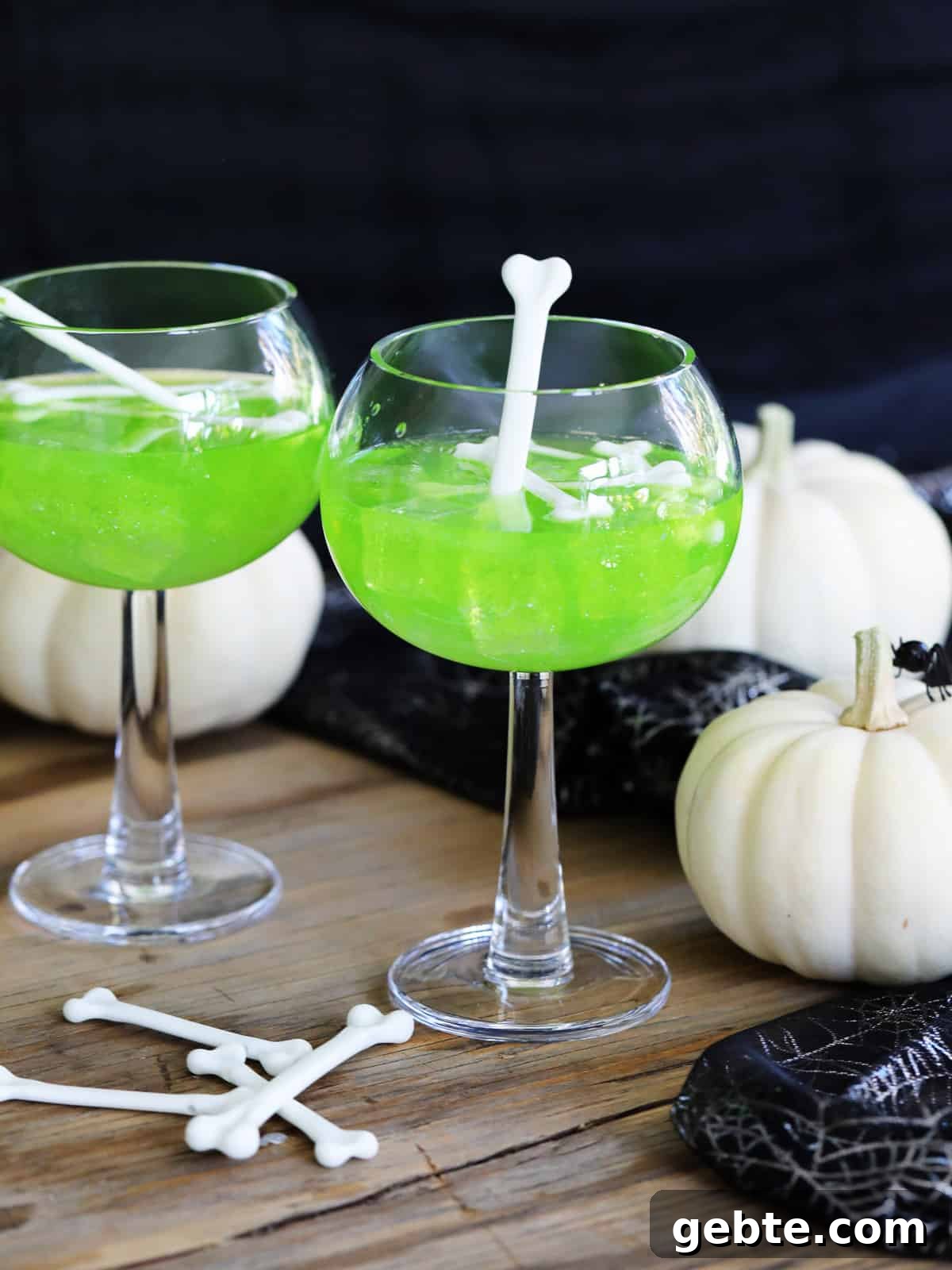 A Halloween party with two green MIdori sour vodka cocktails and garnished with white plastic bones for Halloween cocktails.