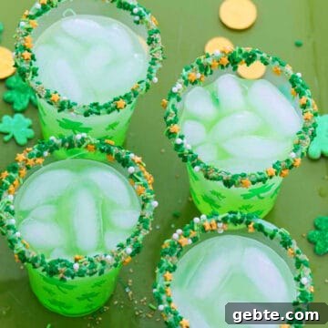 Four glasses of green cocktails for St. Patrick's day on a green tray with gold coins.