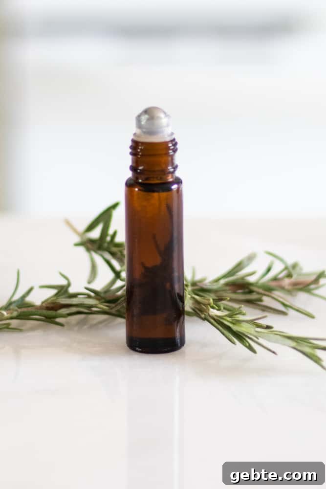 How to Use Rosemary Essential Oil: Blends and DIY Recipes 5 essential oil roller bottle with fresh rosemary behind it