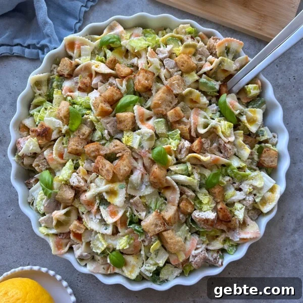 A large, round dish filled with Chicken Caesar Pasta Salad.