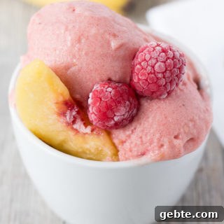 cup of raspberry peach nice cream with bananas and white napkin in background