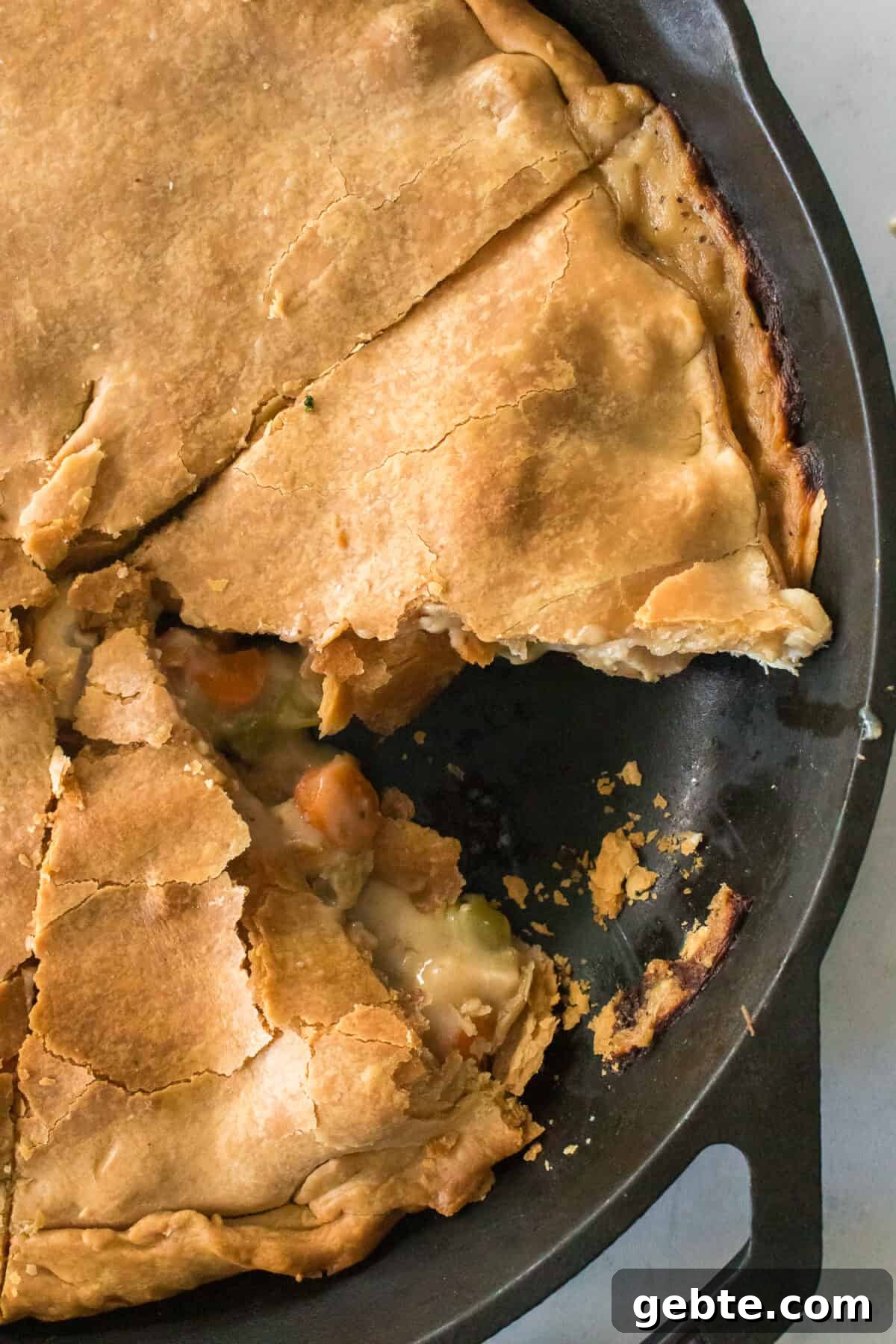 vertical close up shot of cast iron skillet with piece of chicken pot pie missing