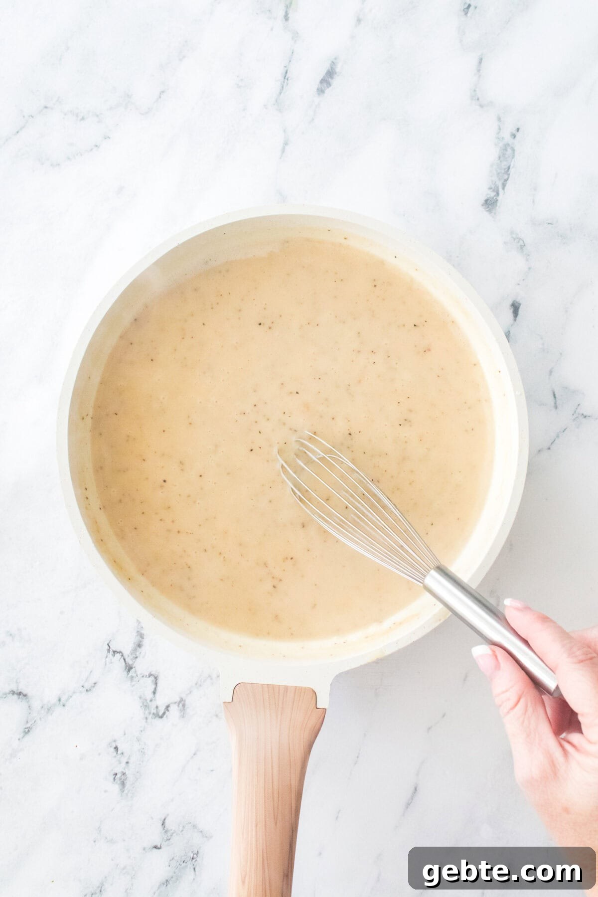 overhead shot of pan making roux with hand whisking