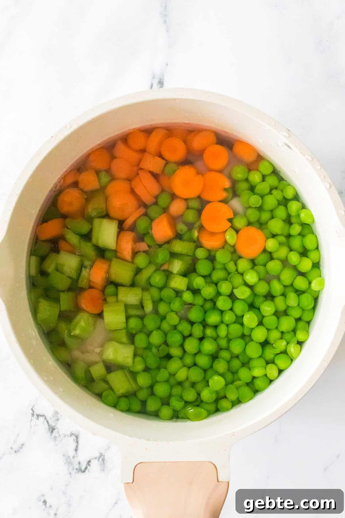 diced chicken, carrots, celery, peas and water in saucepan before cooking