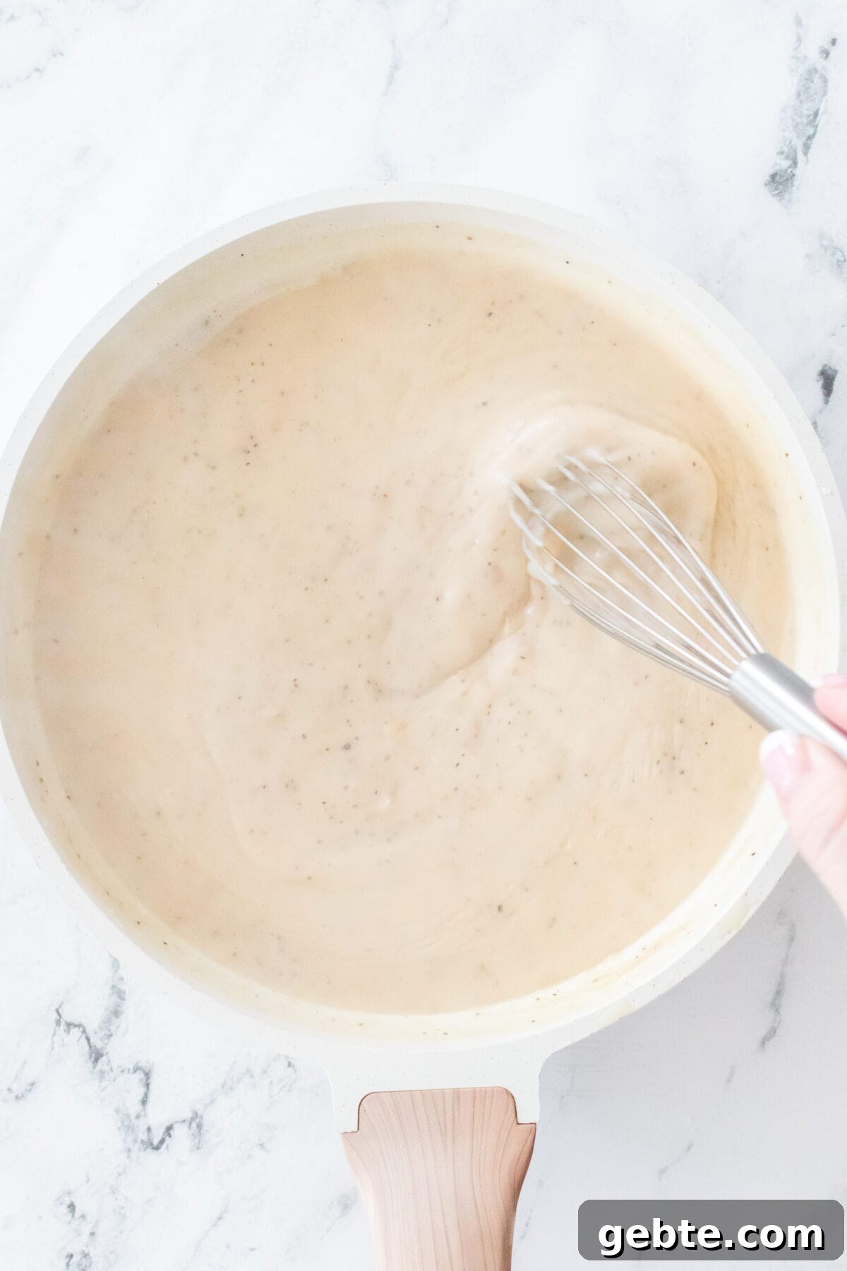 overhead shot of skillet with a roux being made with hand whisking