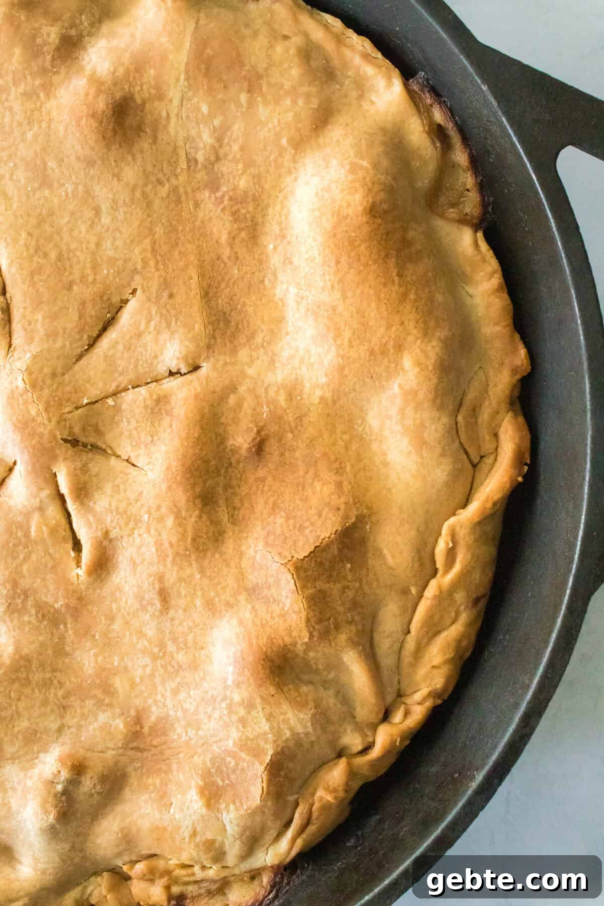 close up vertical shot of flaky pie dough in cast iron skillet for chicken pot pie recipe