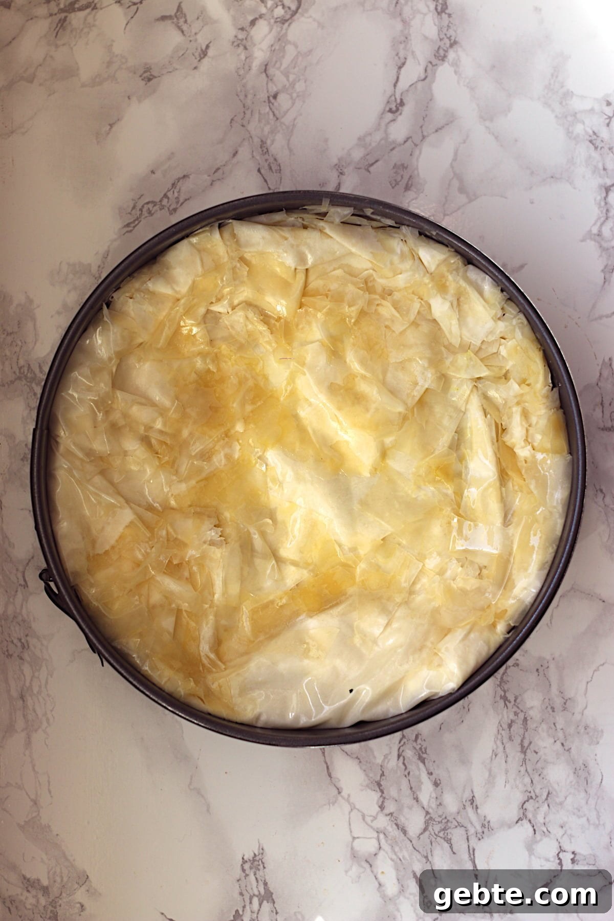 Uncooked meat pie with phyllo crust in a springform pan.