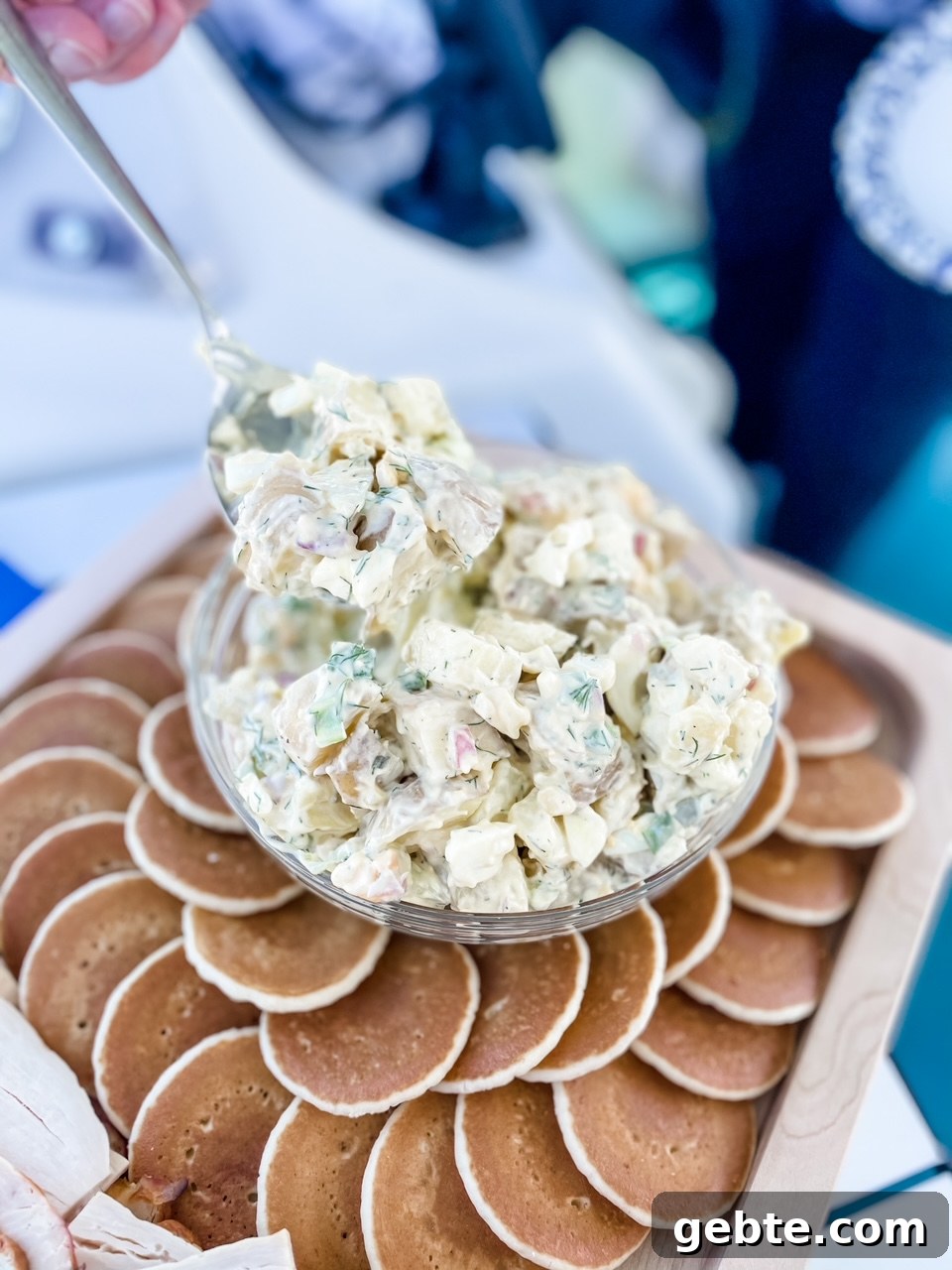 A bowl of the Potato Salad with Dill surrounded by small pancakes on a serving dish