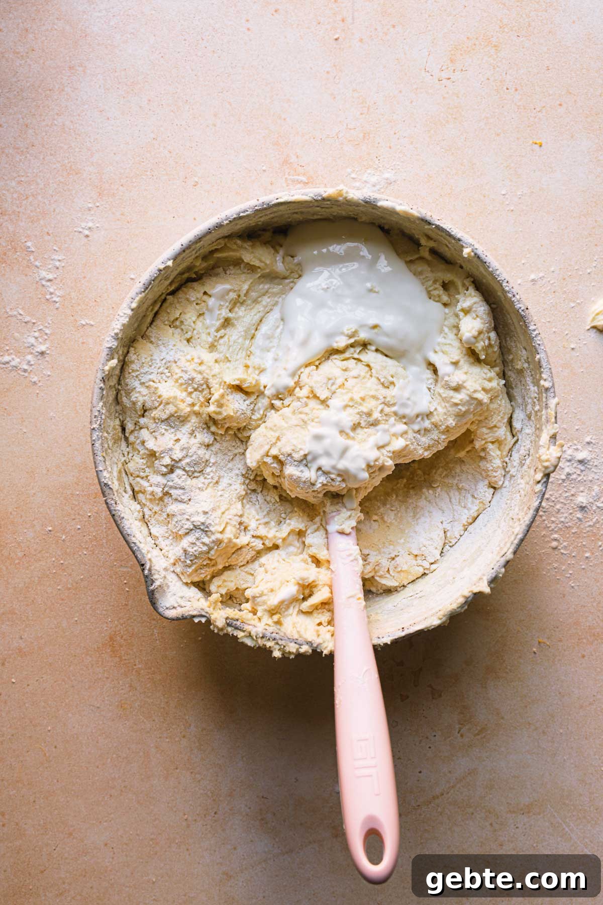 A bowl with cake batter with flour and a spatula.