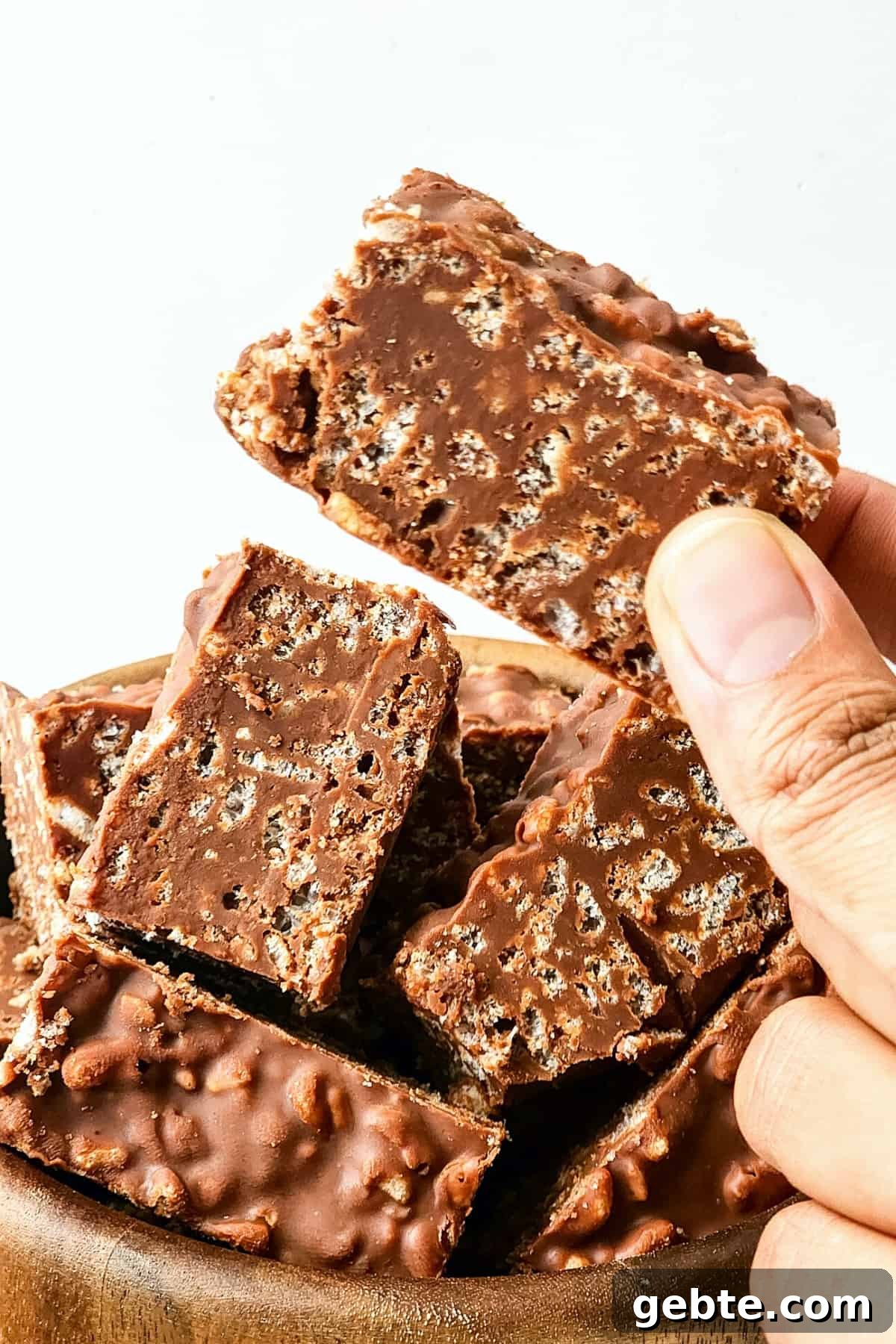 Holding up a piece of chocolate peanut butter crunch bar.