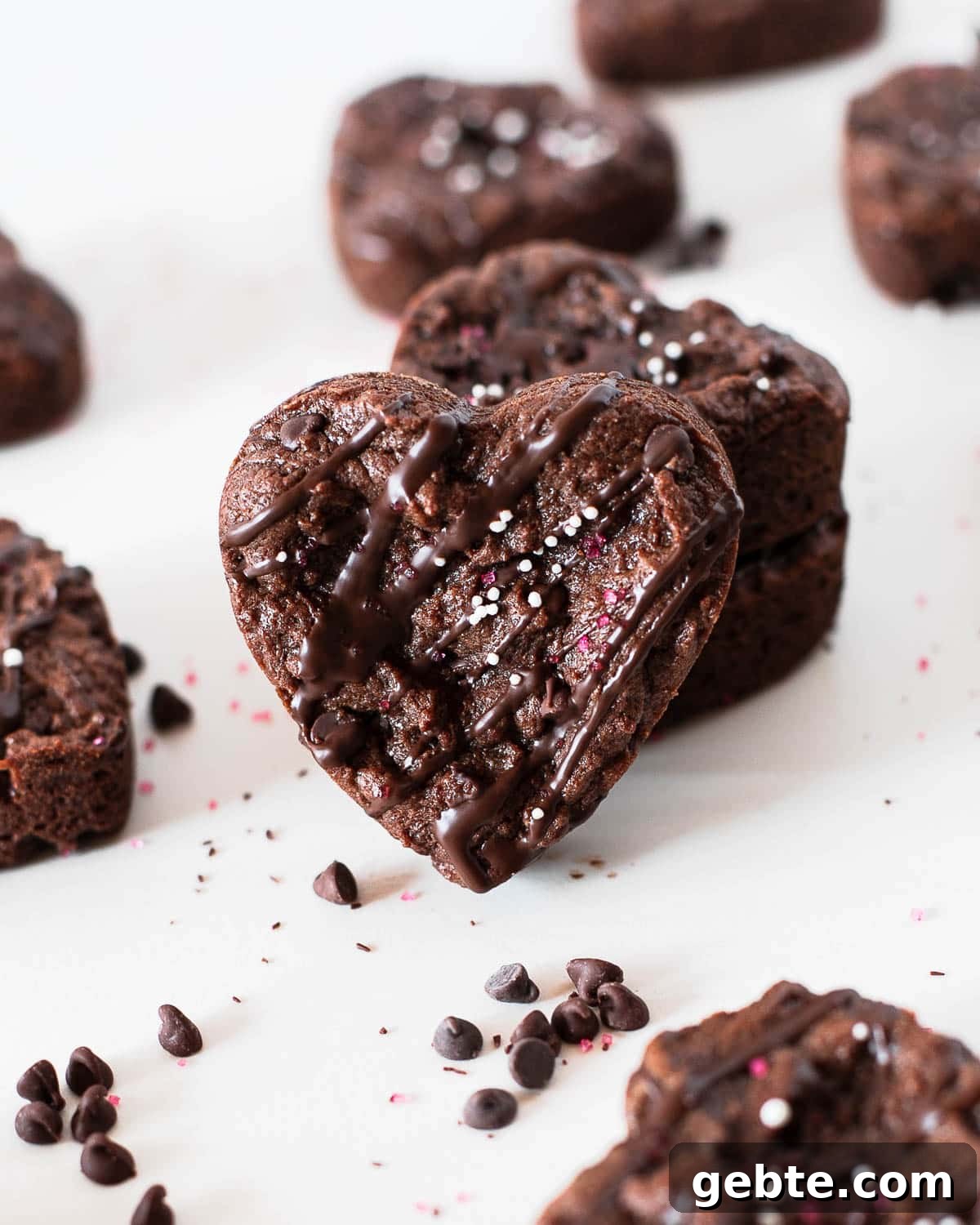heart shaped protein brownies with chocolate chips around on a white surface.
