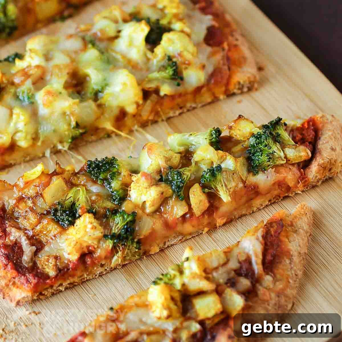 Close up shot of multiple slices of curry pizza on a wooden cutting board.