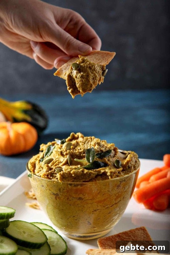 A woman scoops a helping of Sage Pumpkin Hummus out of container