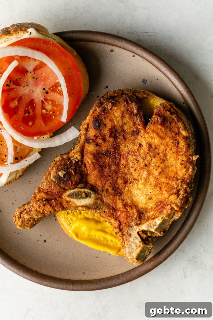 fried pork chop on bread with mustard, onions and tomatoes