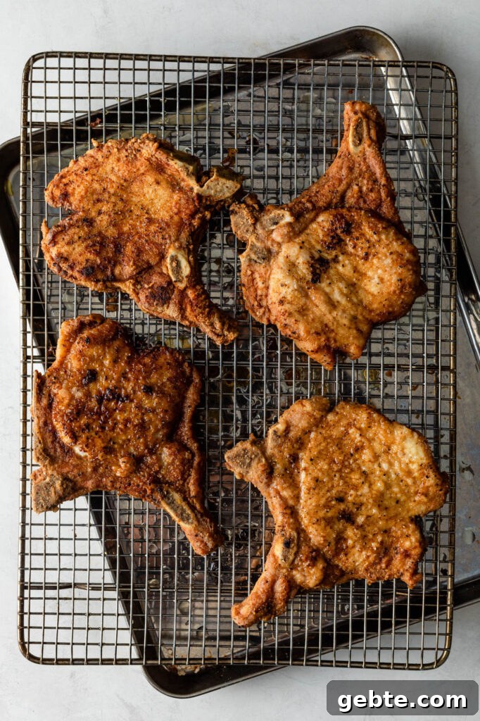 four fried pork chops on a wire rack